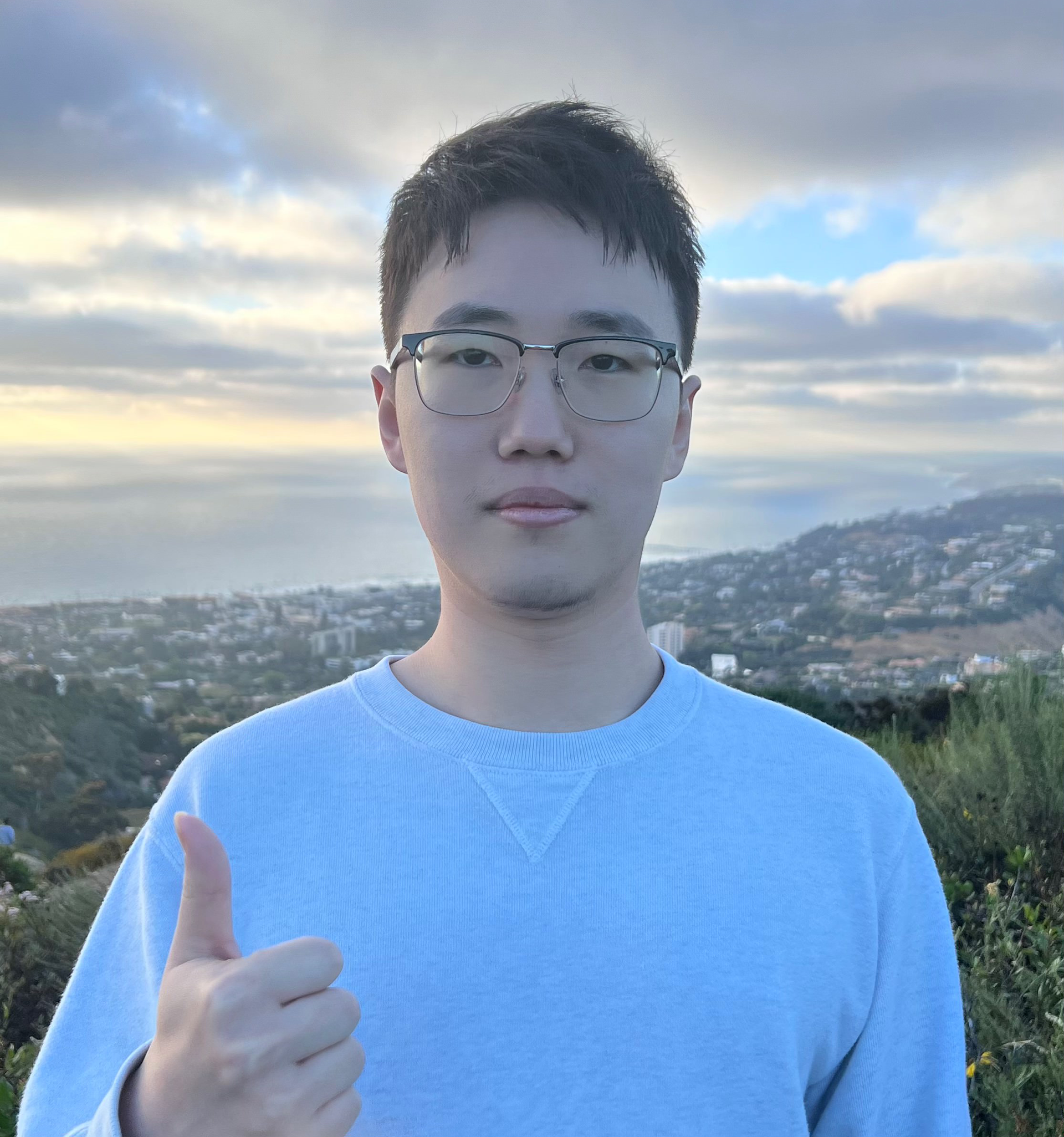 Shaoze Zhou outdoors with the coast in the background